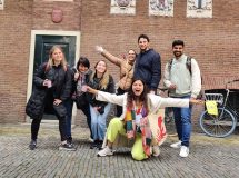 Group of people smiling and posing on the street with decorative wall tiles.