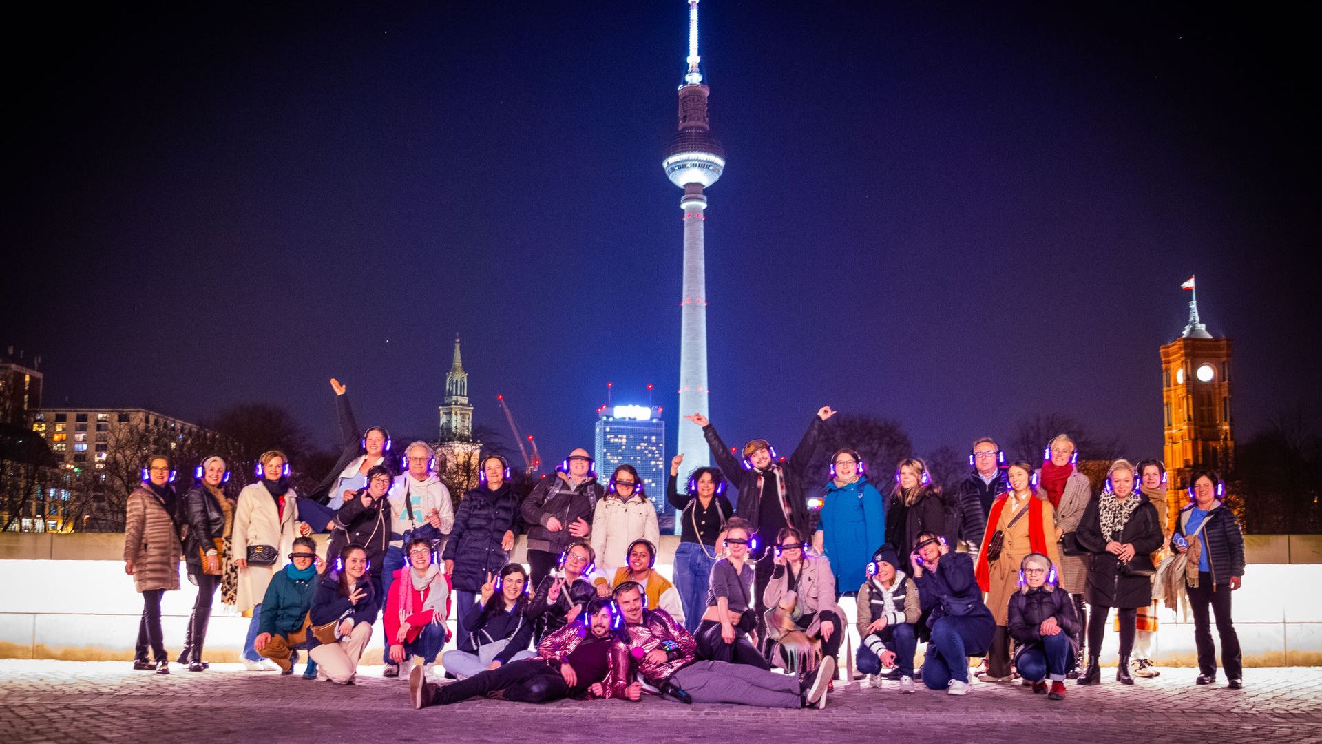 Group of people posing at night with a lit tower in the background.