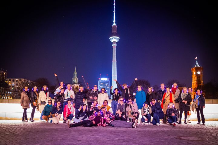 Group of people posing at night with a lit tower in the background.