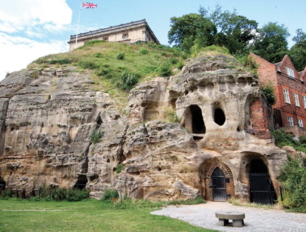 Nottingham Caves a large stone building with a mountain in the background