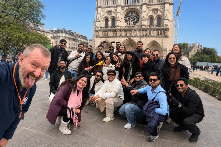 Group of people posing in front of a cathedral with a man taking a selfie.
