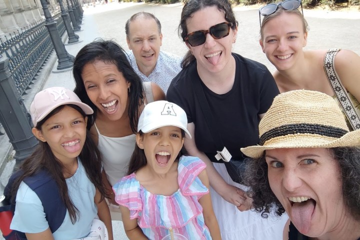 Group of seven people smiling and posing outdoors, showing tongues.
