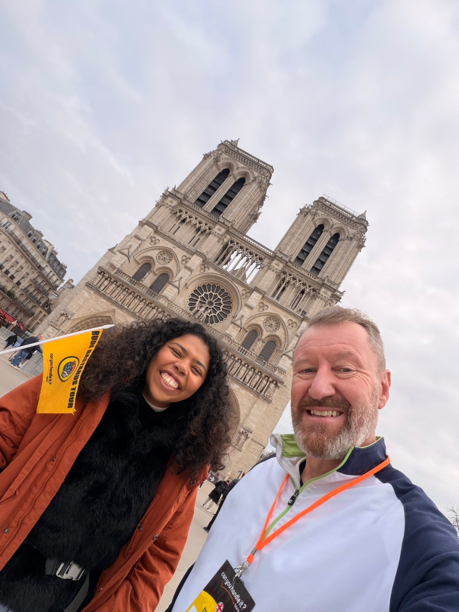 Two people smiling in front of Notre-Dame Cathedral in Paris.