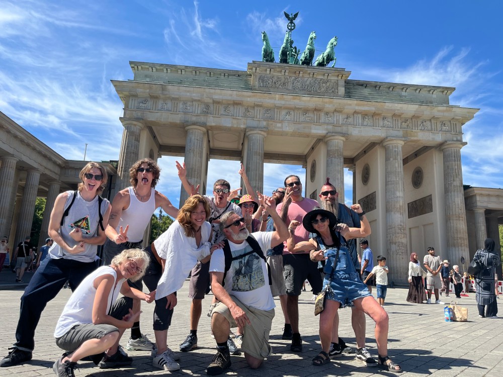 Group posing joyfully in front of the Brandenburg Gate, Berlin.