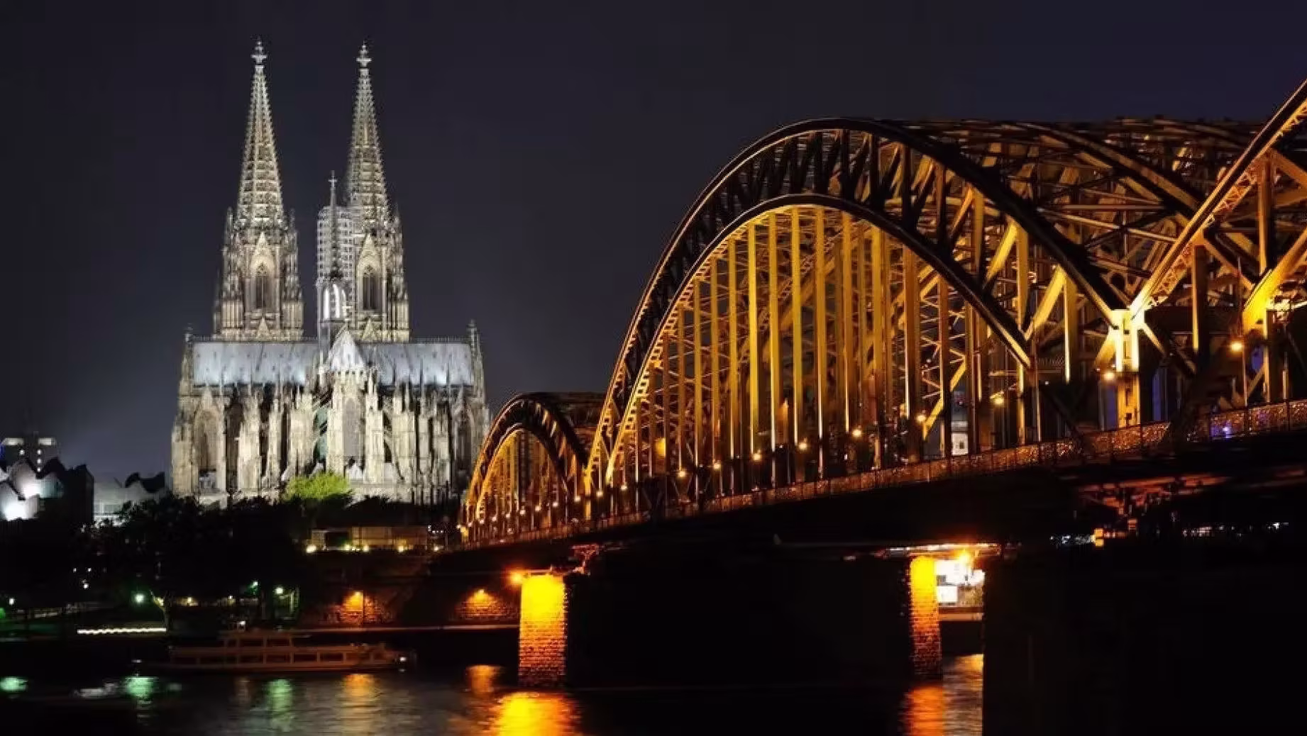 Night view of Hohenzollern Bridge with love locks and illuminated Cologne Cathedral