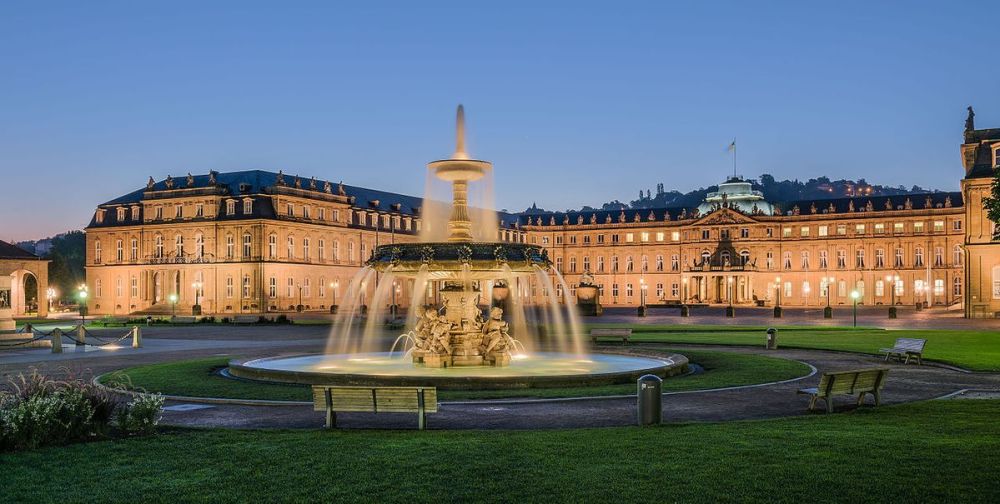 Illuminated palace and fountain at dusk with a clear sky.