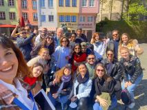 Group of people smiling outdoors in front of colorful buildings.