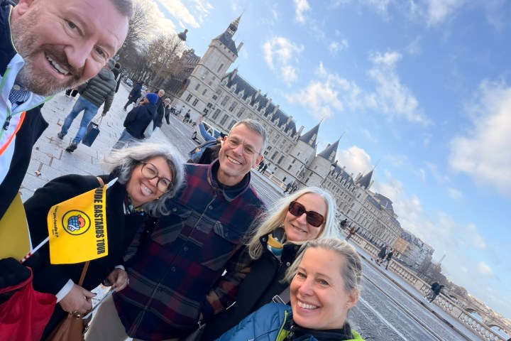 Group of five people smiling with a historic building in the background.