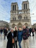 Four people posing in front of Notre-Dame Cathedral in Paris.