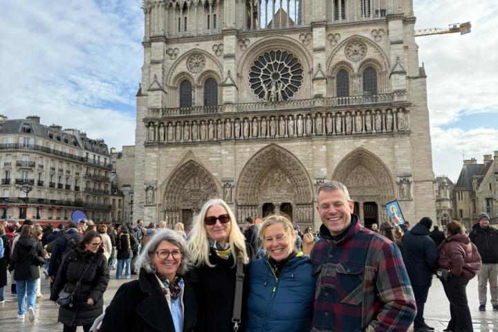 Four people posing in front of Notre-Dame Cathedral in Paris.