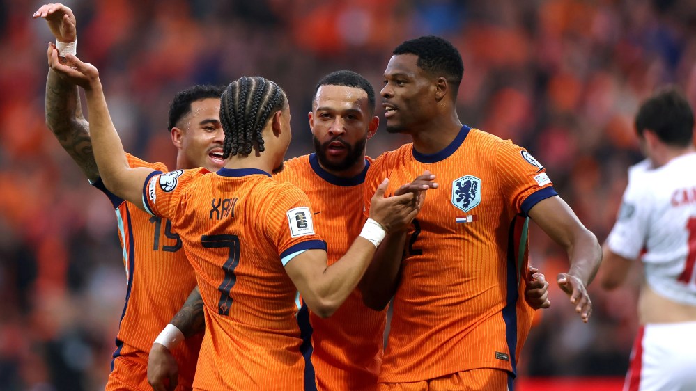 Soccer players in orange uniforms celebrate on the field.
