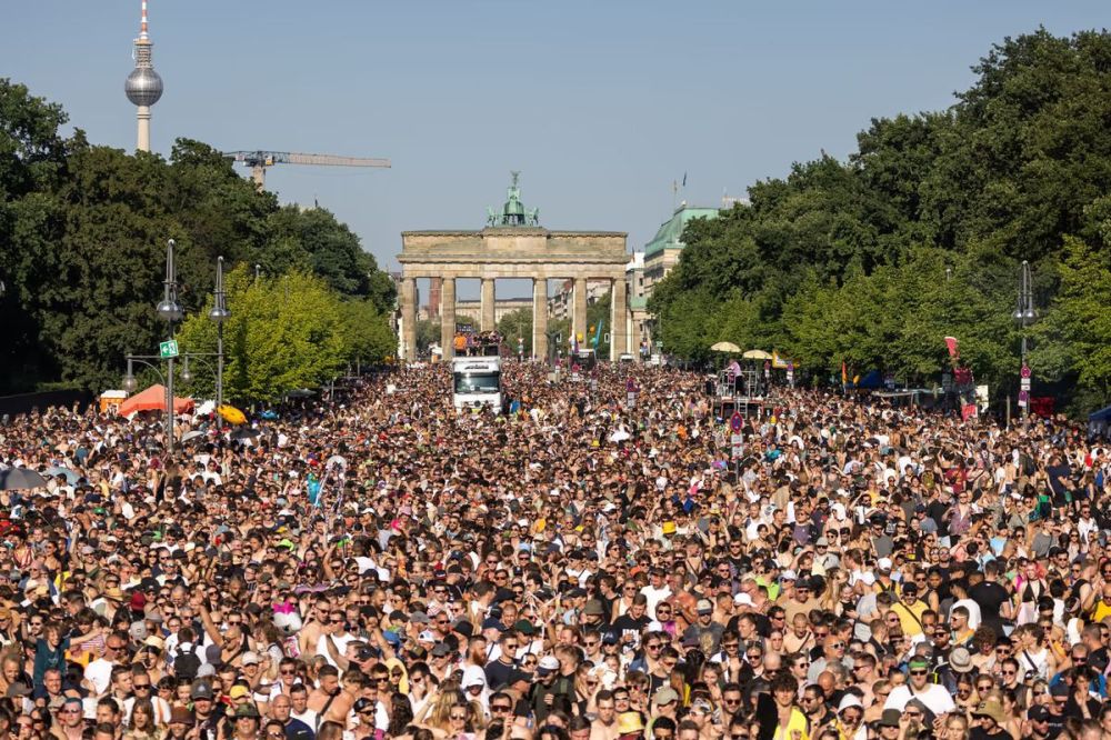 Large crowd gathered in front of Brandenburg Gate on a sunny day.