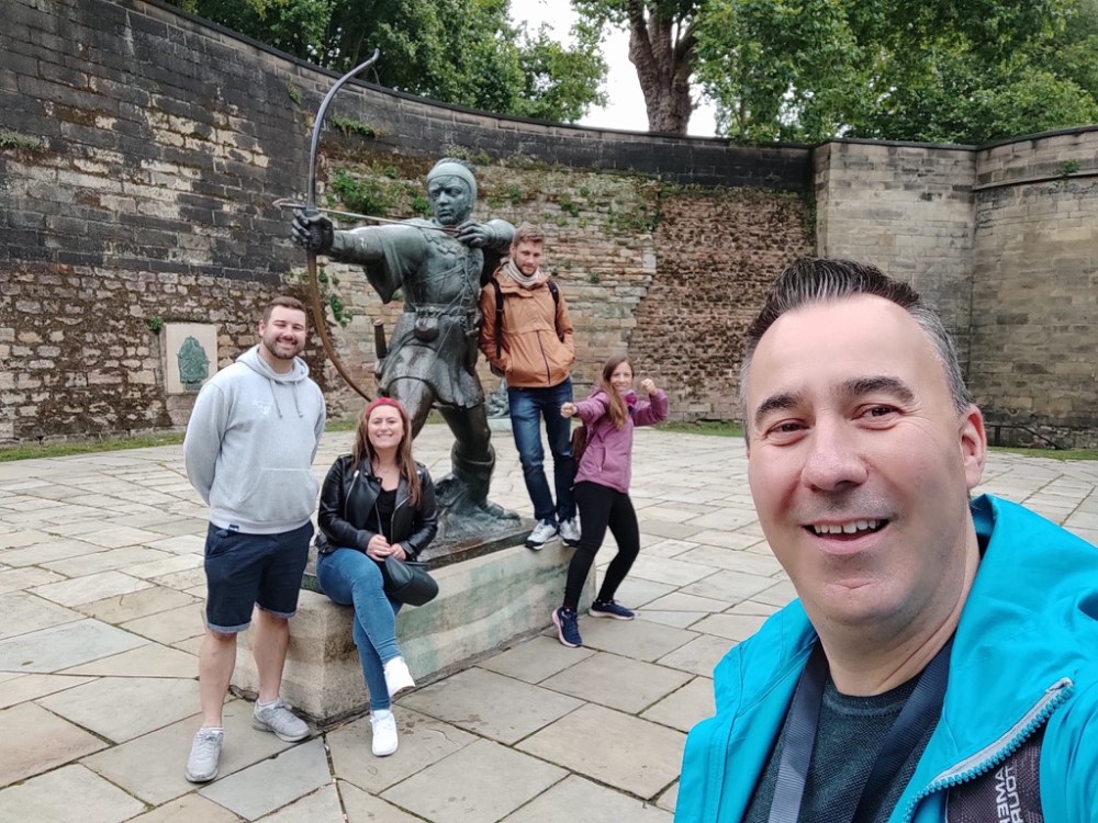 Group of people posing in front of a statue of an archer in a courtyard.