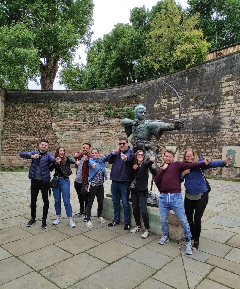 Group posing with a statue of an archer in a courtyard.