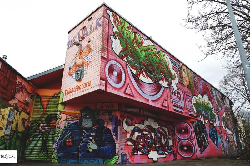 Vibrant graffiti on a large building with murals and colorful designs.