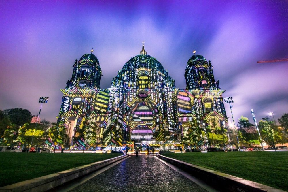 Colorful lights projected on a large domed building at night.