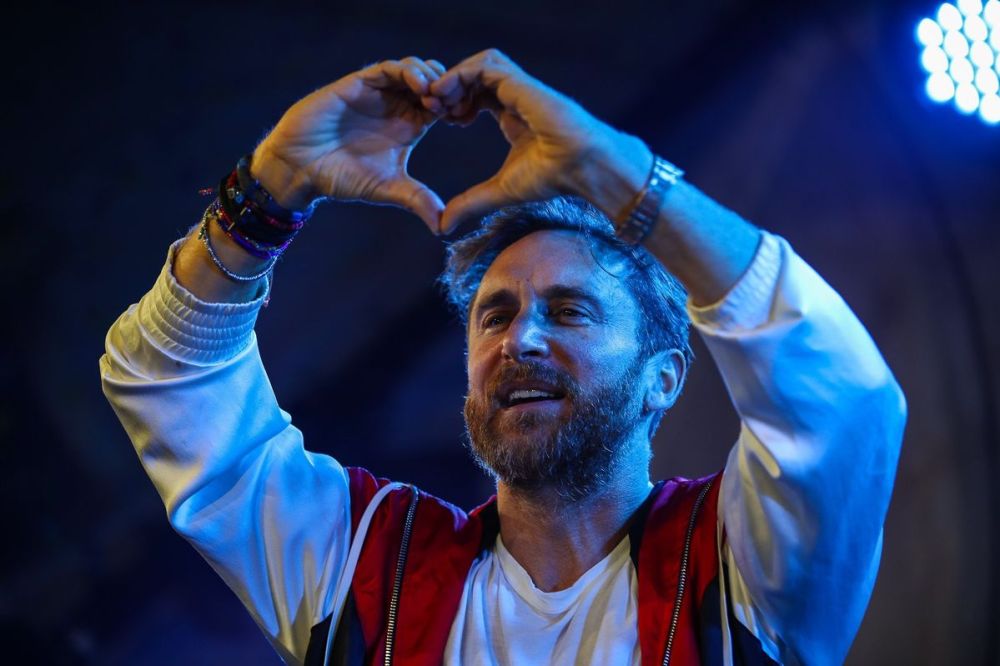 Man in white and red jacket making heart shape with hands.