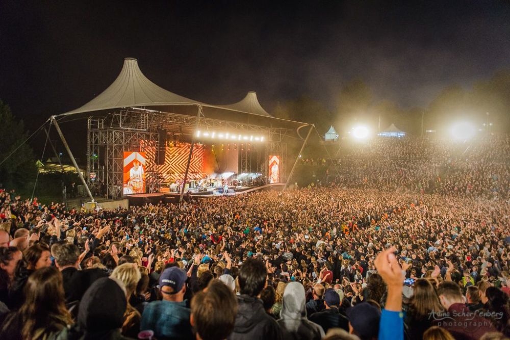 Large outdoor concert at night with a packed audience and illuminated stage.