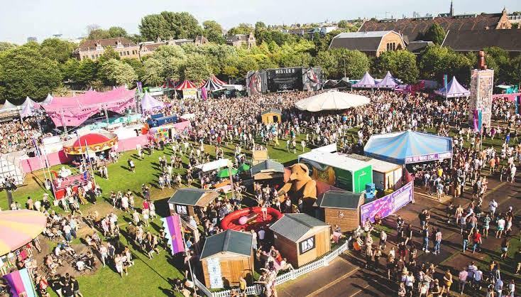 Aerial view of a crowded outdoor festival with tents and a stage.